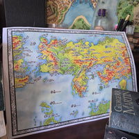 Load image into Gallery viewer, Map of Essos from 'A Song of Ice and Fire' on a table with books and pens.
