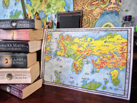 Load image into Gallery viewer, Map of Westeros and Essos from 'A Song of Ice and Fire' series books on a wooden surface.
